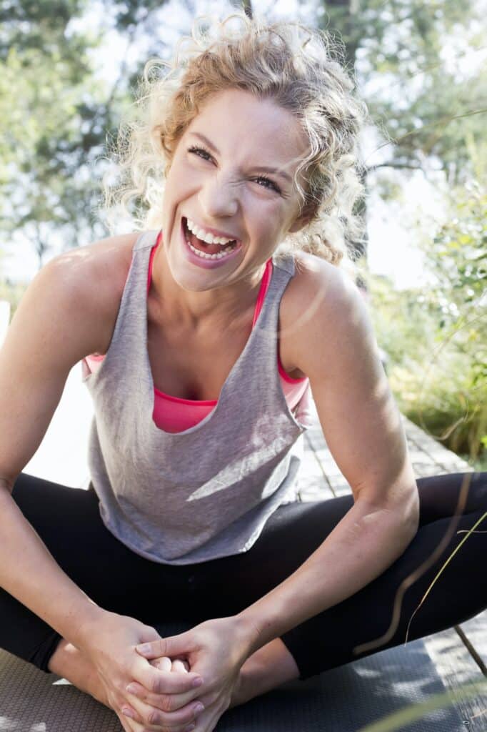 Young woman in sports clothes sitting on floor, laughing